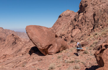 A local bedouin on its way to the summit of Mount Catherine, the highest mountain in Egypt. Panoramic view on surrounding red mountains, rock walls and huge boulders of amazing forms.