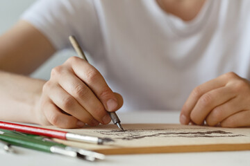 Hands of young woman holding fountain pen, sketching in an album.