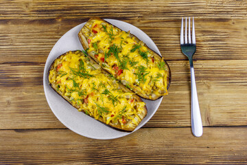 Baked stuffed eggplants on a wooden table. Top view. Healthy food and dieting concept