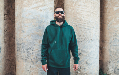City portrait of handsome hipster guy with beard wearing green (watercolor) blank hoodie or sweatshirt with space for your logo or design. Mockup for print