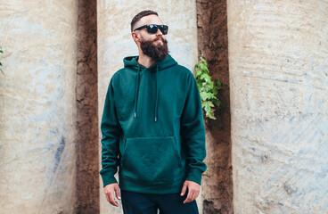 City portrait of handsome hipster guy with beard wearing green (watercolor) blank hoodie or sweatshirt with space for your logo or design. Mockup for print
