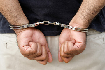 Arrest the offender. Prison male criminal standing in handcuffs with hands behind back. 
