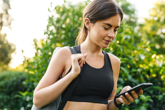 Image of young athletic sportswoman using mobile phone