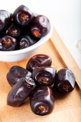 Dried date fruit in bowl on wooden table background.