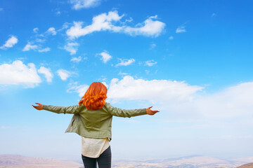 Happy beauty red-haired woman in green jacket open hands outdoors enjoying freedom nature on sky...