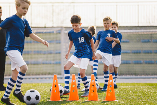 Happy School Kids Practice Soccer With Young Coach. Male Junior Level Sports Team Training Football Outdoor on Grass Venue. Summer Sports Camp For Kids