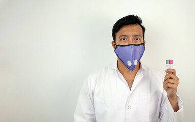 a medical professional in white coat and protective mask holding covid 19 sample vials in hand