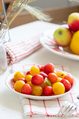 Ripe red and yellow plums and apples on a vintage plate. On light background. Scandinavian style.