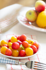 Ripe red and yellow plums and apples on a vintage plate. On light background. Scandinavian style.