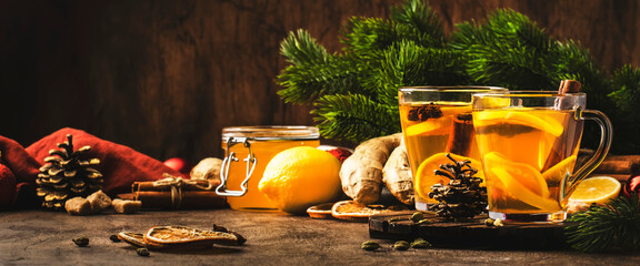 Healing black winter tea with ginger, honey, lemon. Immune booster drink in glass cup on rustic...