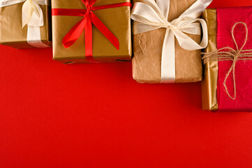 Different christmas gift boxes on red background, top view.