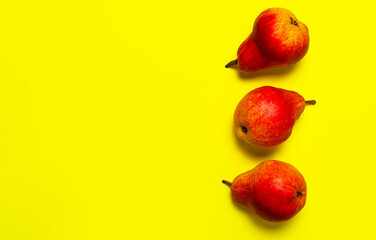 Juicy ripe fresh red pears on yellow background flat lay top view copy space. Creative background with pears and green leaves. Fruit background, organic healthy food. Harvest concept