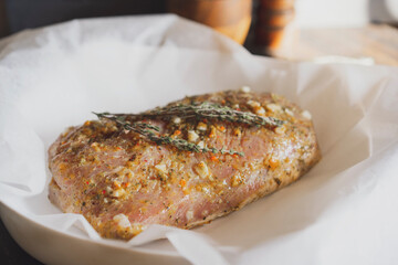 Fresh pork raw carbonade, meat marinated and prepared for roast with garlic, herbs, thyme, spices, pepper on wooden chopping board, rustic table at kitchen. Selective focus, copy space.