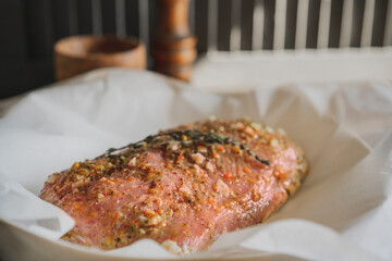 Fresh pork raw carbonade, meat marinated and prepared for roast with garlic, herbs, thyme, spices, pepper on wooden chopping board, rustic table at kitchen. Selective focus, copy space.