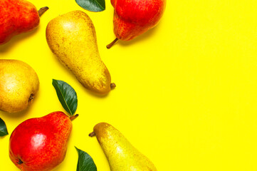 Juicy ripe fresh green and red pears on yellow background flat lay top view copy space. Creative background with pears and green leaves. Fruit background, organic healthy food. Harvest concept