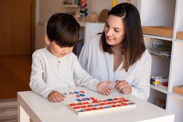 Fototapeta premium Kid learning to write and read with a alphabet and mother or teacher help. Homeshooling. Learning Community. Montessori School