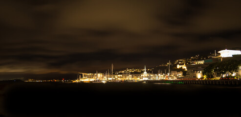 Fototapeta premium Wellington city waterfront at night: Lit-up houses on the slopes of Mt Victoria and street lights shining over calm water of Wellington Harbour.
