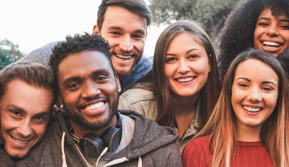 Happy millennial friends from diverse cultures and races having fun in front of smartphone camera -...