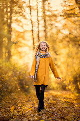 Fototapeta na wymiar A girl in a yellow coat walks in an autumn park