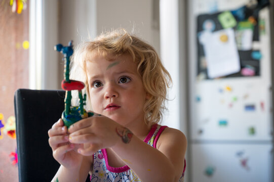 Cute girl painting wooden giraffe push puppet.
