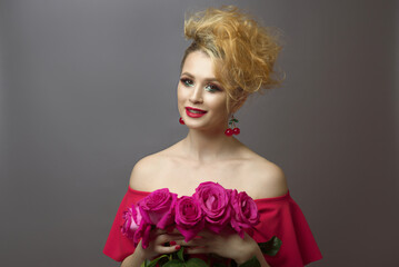 young red-haired woman in a red dress holding a rose flowers.  gray background