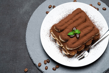 Classic tiramisu dessert on ceramic plate on concrete background