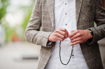Stylish pakistani man wear in jacket, hold tasbeeh or prayer beads on hand.