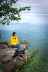 Fototapeta premium Asian woman tourist is sitting to see natural view with relax at cliff mountain at Sai Thong National Park at Chaiyaphum in Thailand.