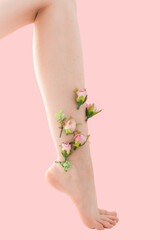 Woman's thin unshaven leg with pink flowers on a pink background. Feminism