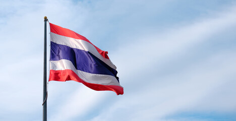 Waving Thailand flag with blue sky background .