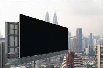 Blank black road billboard with Kuala Lumpur cityscape background at day time. Street advertising poster, mock up, 3D rendering. Side view. The concept of marketing communication.