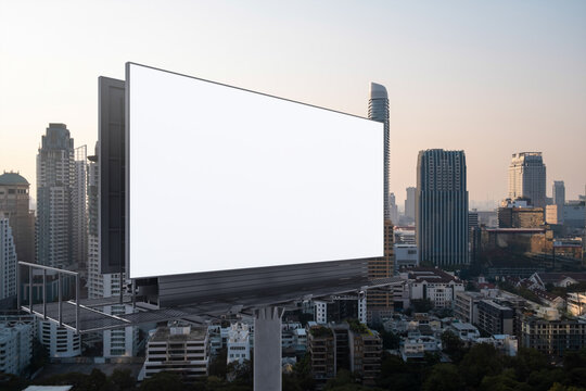 Blank white road billboard with Bangkok cityscape background at sunset. Street advertising poster, mock up, 3D rendering. Side view. The concept of marketing communication to promote or sell idea.