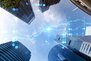 FOREX and stock market chart hologram on low, wide angle view of glass and steel contemporary skyscrapers in financial downtown. The concept of international trading. Double exposure.