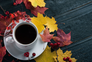 A white espresso Cup on a dark wooden table with colorful autumn leaves copy space