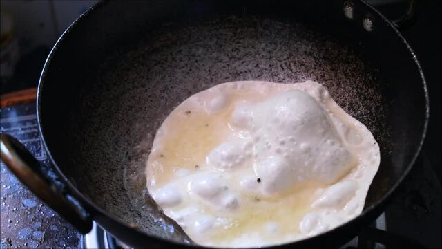 Frying papadam in hot oil.Papadam is a traditional indian snack used as a side dish to main course meal.