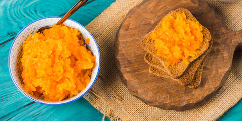 Home made carrot jam made with orange and lemon juice. Healthy vegetable jam for breakfast served with toasted bread on green table.