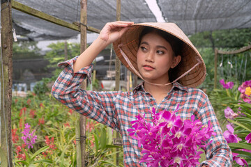 The gardener arranges the orchid garden holding the hat. And holding orchids In the orchid garden