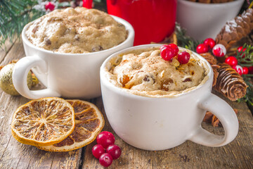 Christmas fruitcake in mug. Simple and fast recipe idea for Christmas breakfast, mugcake in microwave with traditional winter spices and fruits, on xmas decorated wooden background copy space