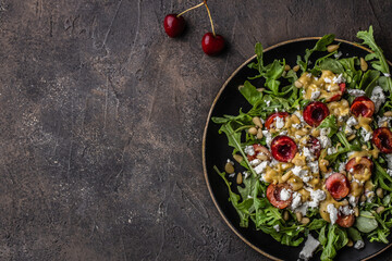 Salad with arugula, cherries, goat cheese, pine nuts, mustard -olive oil dressing. Copy space