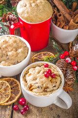 Christmas fruitcake in mug. Simple and fast recipe idea for Christmas breakfast, mugcake in microwave with traditional winter spices and fruits, on xmas decorated wooden background copy space