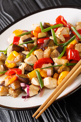 stir-fried chicken with eggplant, pepper and onion close-up in a plate. Vertical