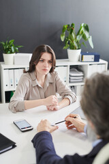 Young woman feeling confused with absurd questions HR manager asking her at job interview, vertical...