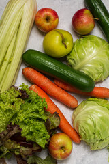 assortment of vegetables on a white table: carrots, celery, cucumbers, zucchini, apples, cabbage, lettuce. The concept of healthy eating. Vegan and vegetarian concept.