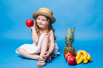 Little girl playing with fruits isolated on a blue background