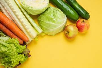 set of vegetables on a yellow background: carrots, celery, cucumbers, zucchini, apples, cabbage, lettuce. The concept of healthy eating. Vegan and vegetarian concept.