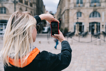 Modern woman walking in Bordeaux city and taking shot with phone