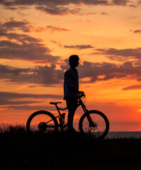 Fototapeta na wymiar Silhouette of a young man with a Bicycle against the background of a sunset.