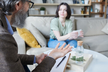 Psychologist sitting in front of young woman asking questions about her past during therapy session