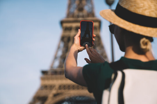 Woman taking pictures of Eiffel Tower on sunny day