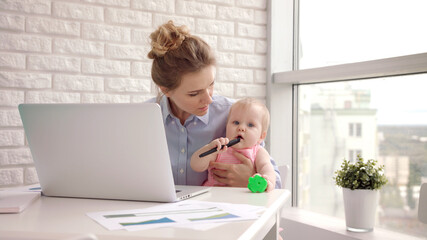 Working mom with child on table. Businesswoman holding toddler girl on hand